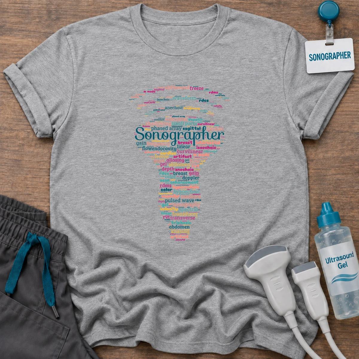 Sonographer Word Cloud t-shirt with a transducer-shaped word cloud of ultrasound terms like Doppler, shadowing, frequency and hyperechoic, with “Sonographer” across the middle, in Sport Grey, by Sono Graphics