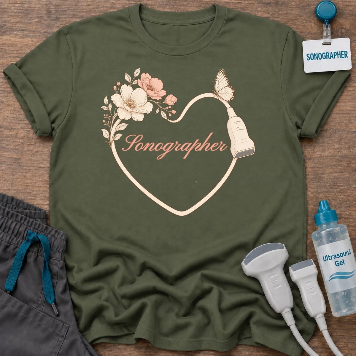 Sonographer Floral Butterfly Heart t-shirt with a heart drawn by a transducer cord with blush flowers, a butterfly and “Sonographer” in peach script, in Military Green, by Sono Graphics