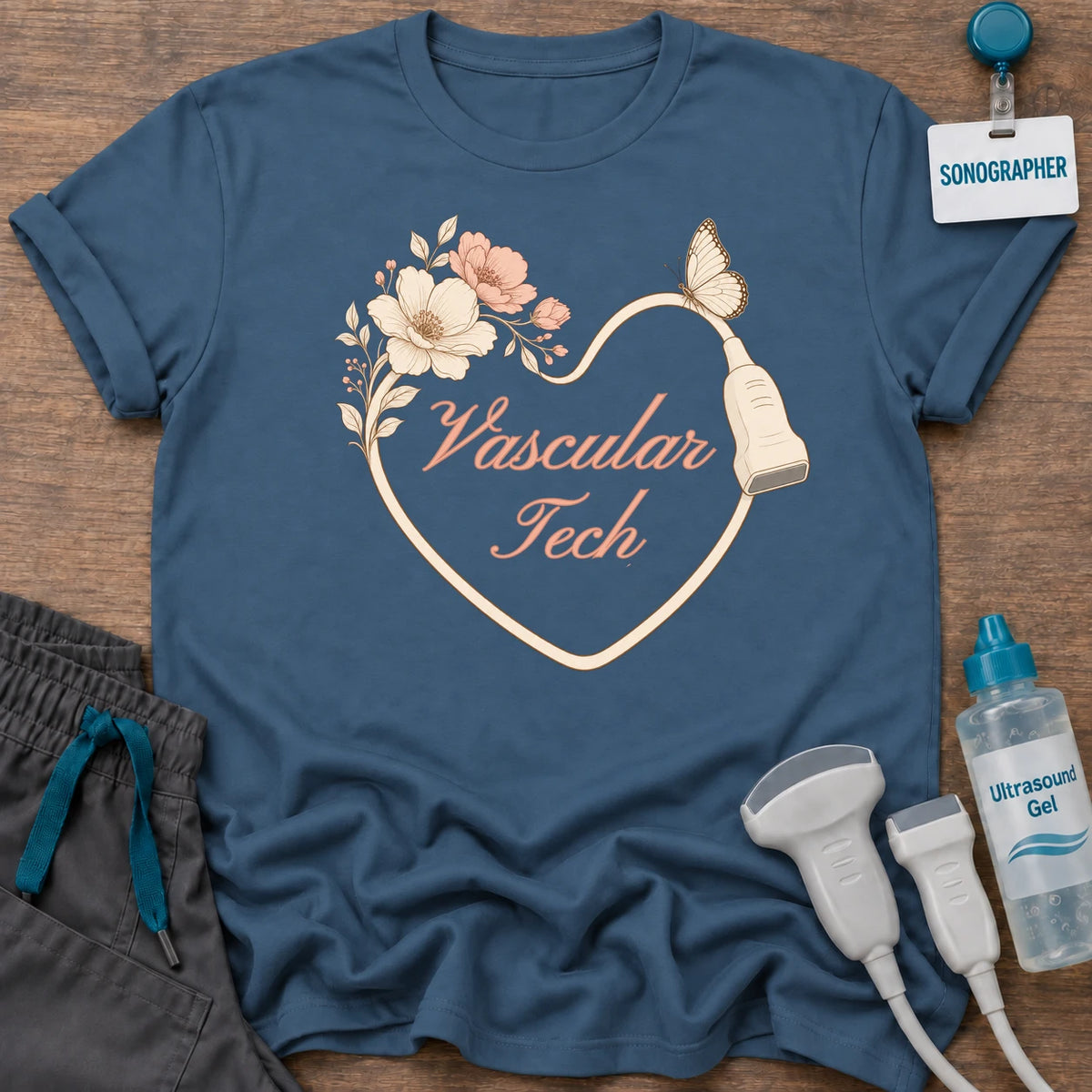 Vascular Tech Floral Heart t-shirt with a heart drawn by a transducer cord with blush flowers, a butterfly and “Vascular Tech” in peach script, in Indigo Blue, by Sono Graphics